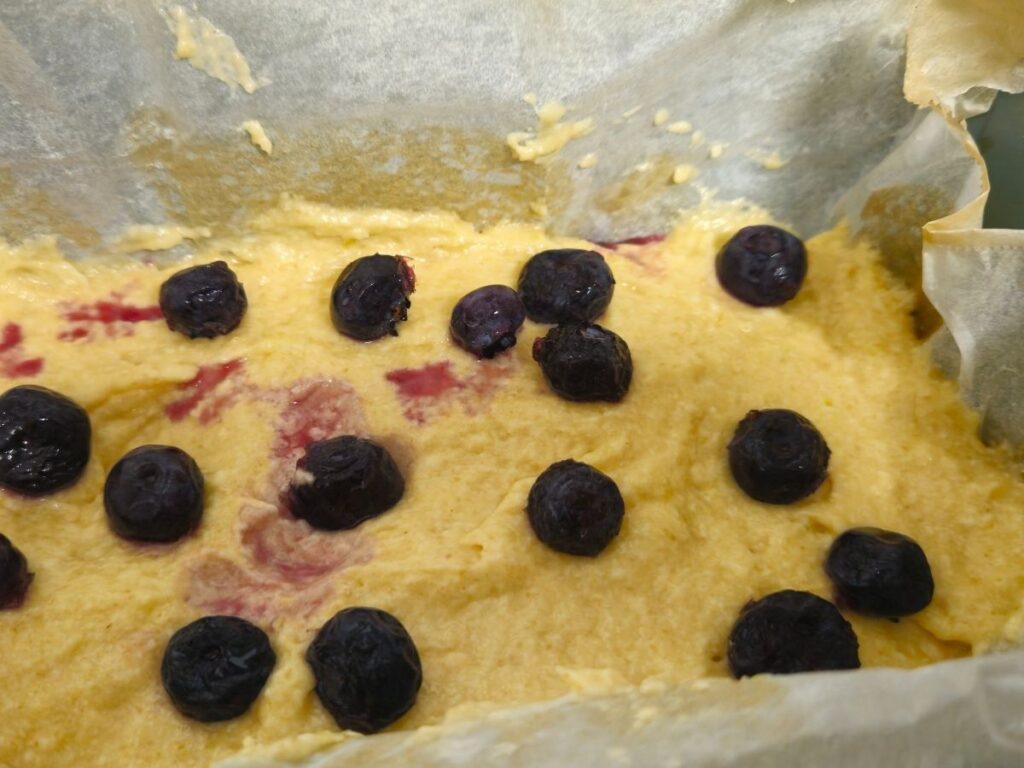 blueberries that have been scattered over raw cake batter