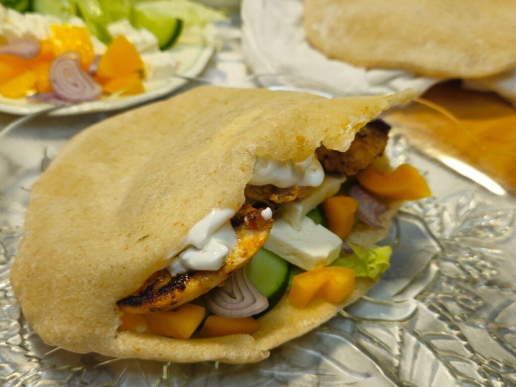 a sourdough pita bread filled with chicken gyro ingredients