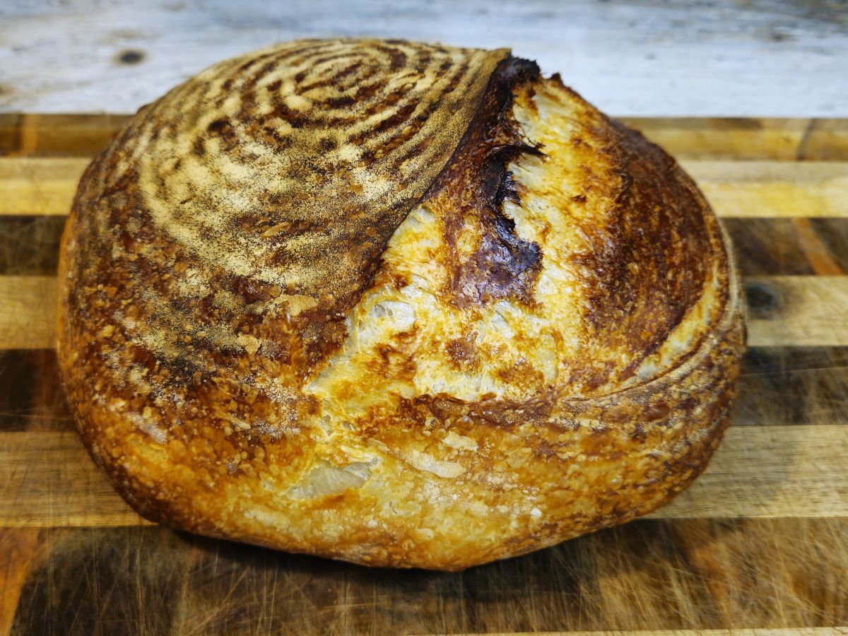 white sourdough bread boule on a wooden chopping board