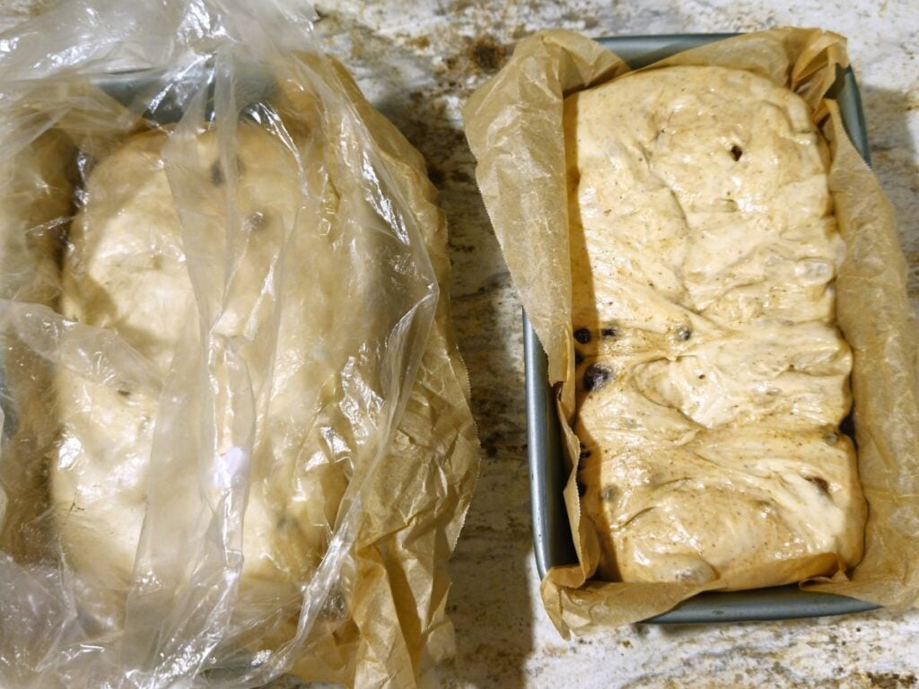 two cinnamon fruit loaves in lined loaf tins left to rise