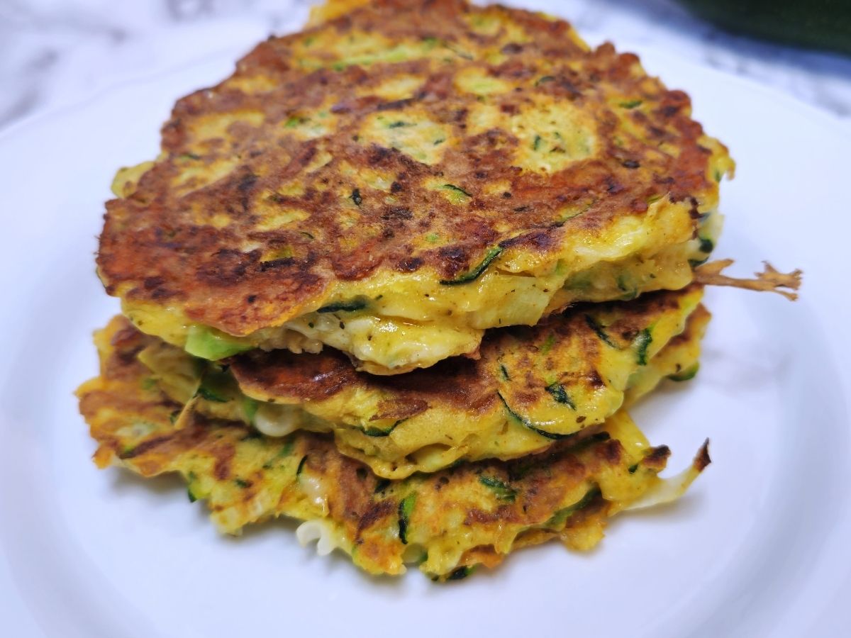 three courgette fritters piled up on a plate