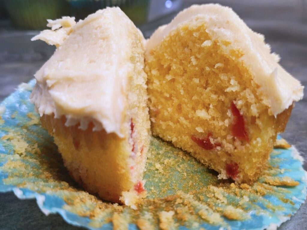 one almond flavored cupcake with maraschino cherries sliced in half