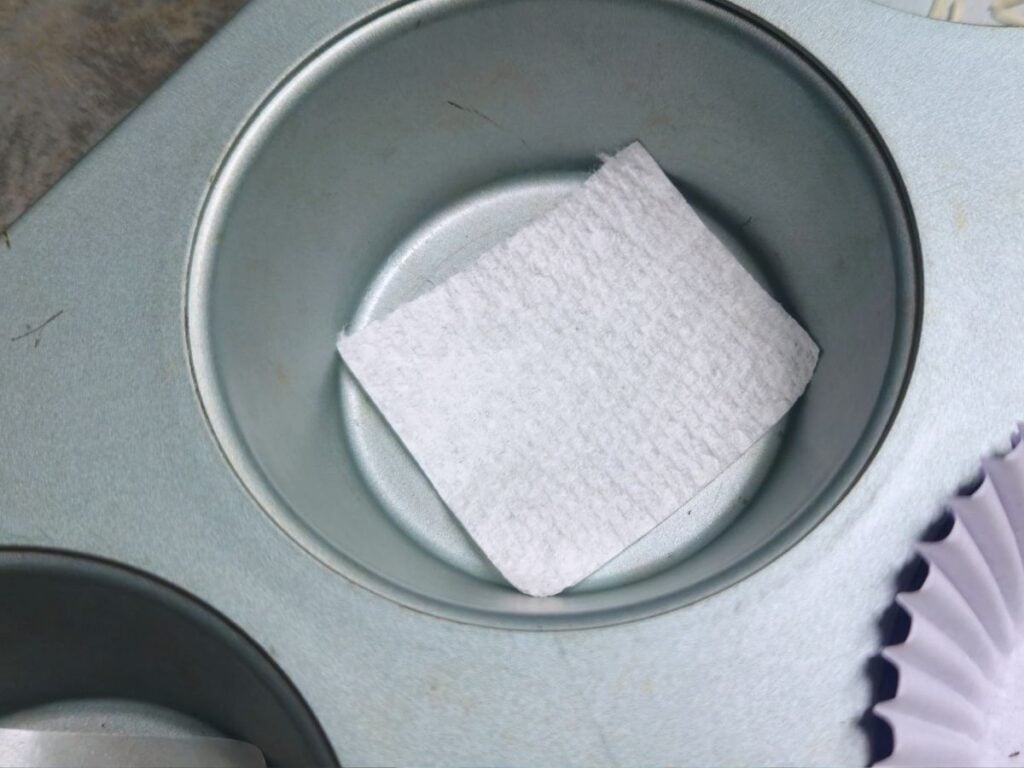 a square of paper towel lining the bottom of a cupcake tin