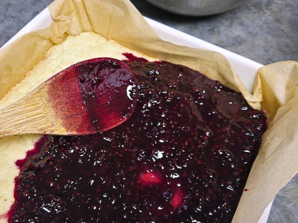 spreading blackberry mixture over shortbread base