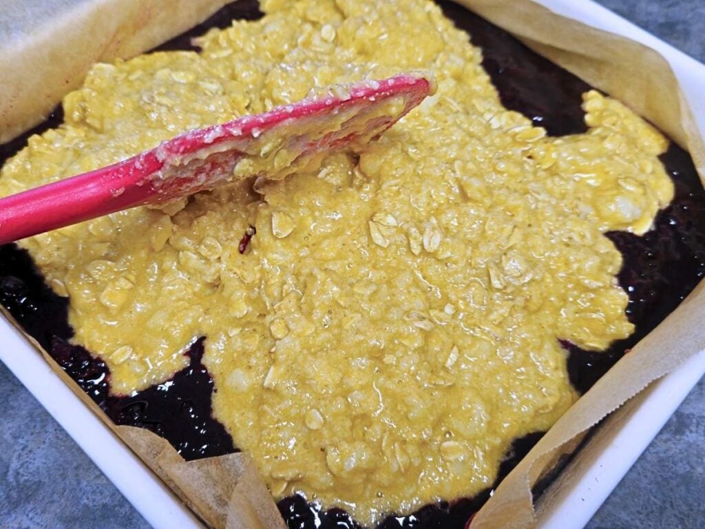spreading oat topping over fruit