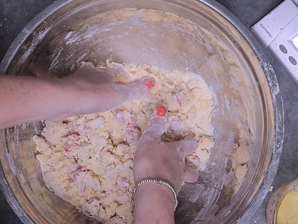 hands bring the scone mixture together to make a dough ball