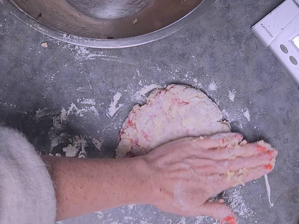 palm of hand flattening scone dough to an inch thick