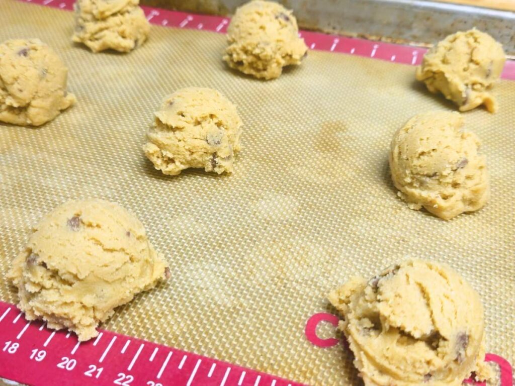 balls of chocolate chip cookie dough on a cookie sheet